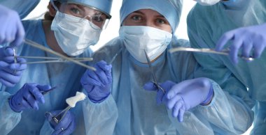 Tıbbi aletleri elinde tutan cerrahların gözünün önünde.