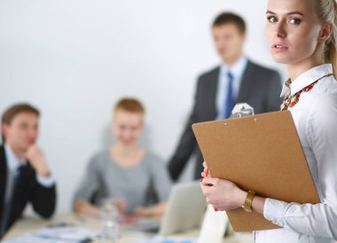 Ofiste çalışan genç bir kadının portresi klasörle duruyor.