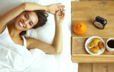 Genç ve güzel bir kadın yatakta yatıyor.