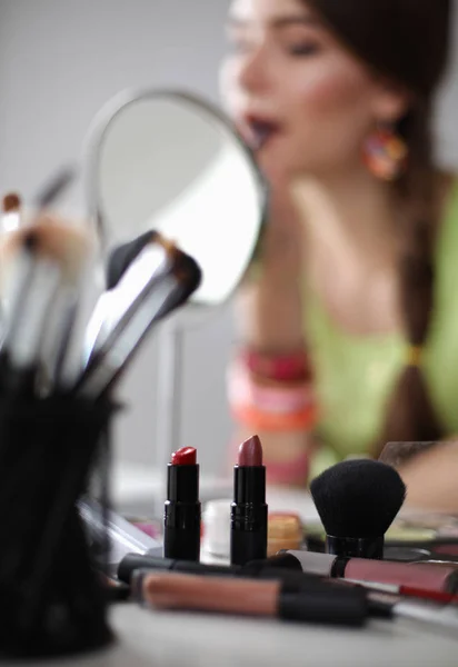 Jonge mooie vrouw maken make-up in de buurt van spiegel, zitten aan de balie — Stockfoto