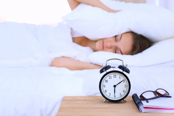 Una mujer joven apagando su despertador por la mañana — Foto de Stock