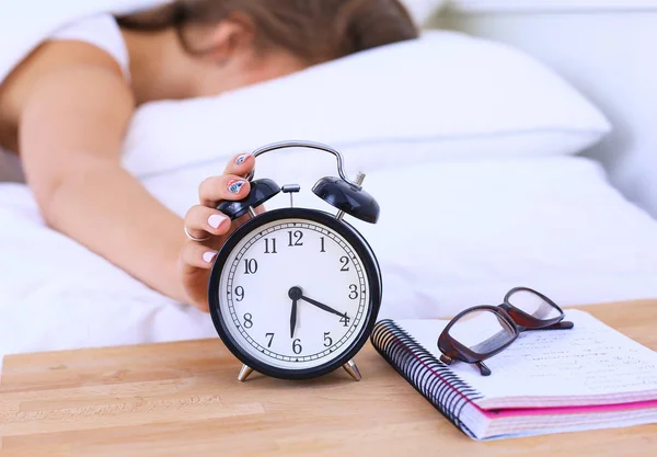 Una mujer joven apagando su despertador por la mañana — Foto de Stock
