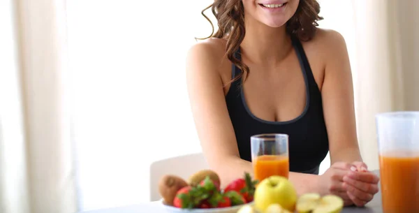 Flicka sitter i köket på skrivbord med frukt och glas med juice — Stockfoto