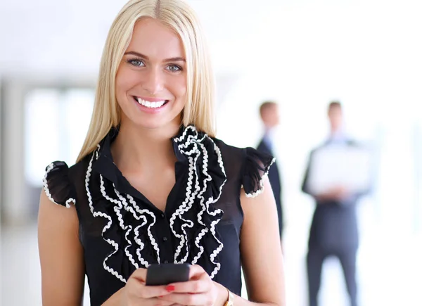 Красивая деловая женщина с мобильным телефоном, стоящая в офисе — стоковое фото