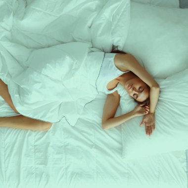 Genç ve güzel bir kadın yatakta yatıyor.