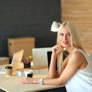 Moda tasarımcıları stüdyoda çalışıyor. Masanın üzerinde oturuyorlar.