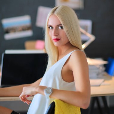 Moda tasarımcıları stüdyoda çalışıyor. Masanın üzerinde oturuyorlar.