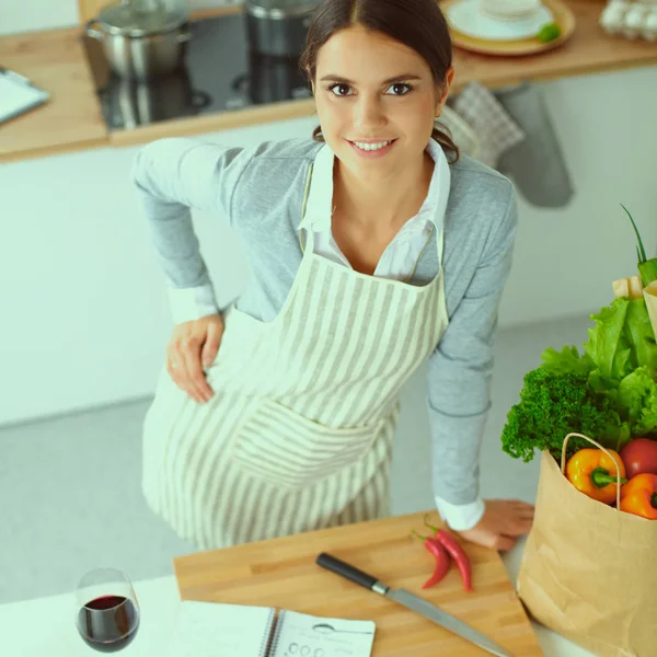 Женщина делает здоровую пищу стоя улыбаясь на кухне — стоковое фото