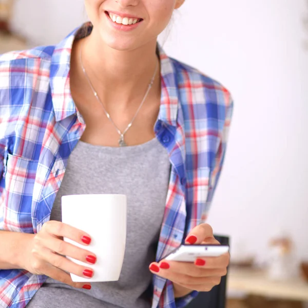 Lächelnde Frau hält ihr Handy in der Küche — Stockfoto