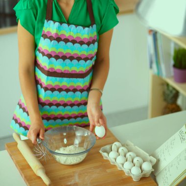 Mutfakta gülümseyen genç bir kadın, arka planda soyutlanmış.