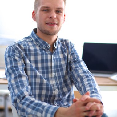 Genç işadamı ofiste çalışıyor, masada oturuyor.