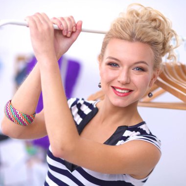 Raf ofiste askıları ile yakınındaki güzel genç stilist