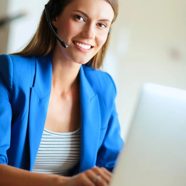 Ritratto di bella donna d'affari che lavora alla scrivania con auricolare e laptop.. — Foto Stock