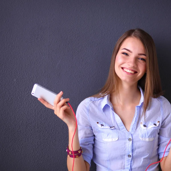 Chica sonriente con auriculares sentados en el suelo cerca de la pared — Foto de Stock