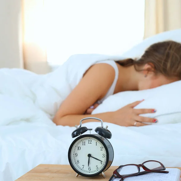 Una mujer joven apagando su despertador por la mañana — Foto de Stock