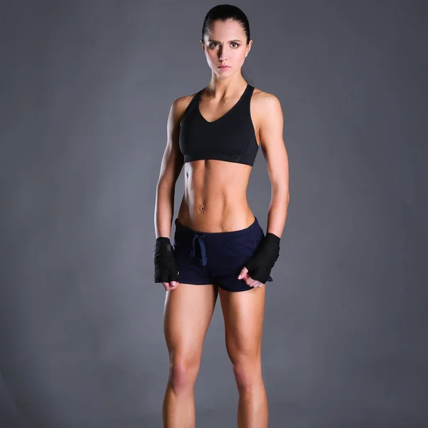 Мускулистая молодая женщина позирует в спортивной одежде на черном фоне — стоковое фото
