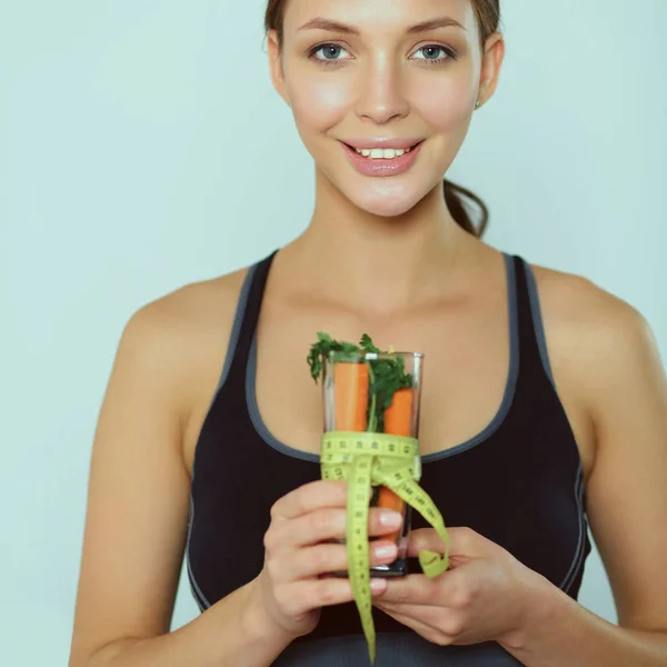 Kvinna som håller ett dricksglas fullt av färsk fruktsallad med ett måttband runt glaset — Stockfoto