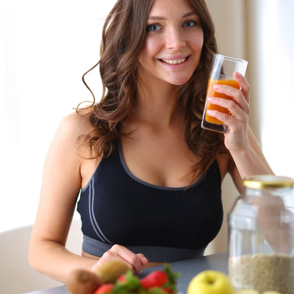 Menina sentada na cozinha na mesa com frutas e óculos com suco — Fotografia de Stock