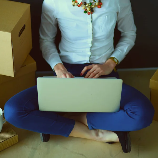 Mujer sentada en el suelo cerca de una caja con portátil — Foto de Stock