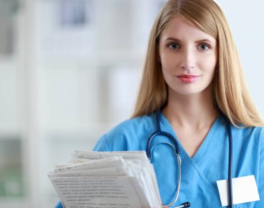 Hastane koridorunda klasörlü kadın doktor portresi.