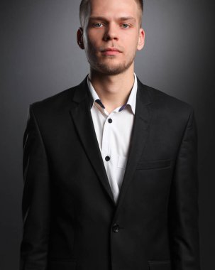 Gri arka plan üzerinde duran gülümseyen genç adam portresi