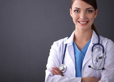 Steteskoplu doktor kadın gri duvarın yanında duruyor.