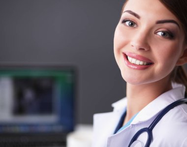 Gri arka planda oturan kadın doktor