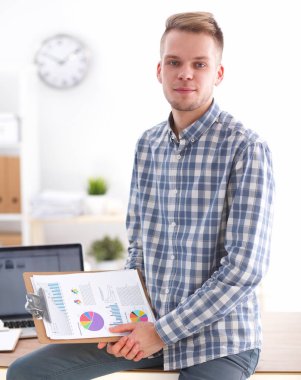 Ofiste oturan kırmızı klasör ile gülümseyen iş adamı