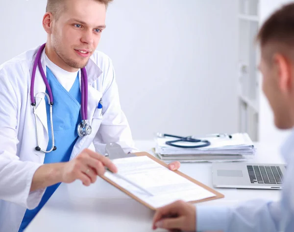 Médico macho dando pasta paciente com papel em seu escritório, isolado — Fotografia de Stock