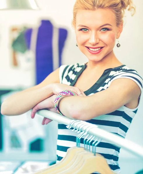 Mooie jonge stylist bij rek met hangers — Stockfoto