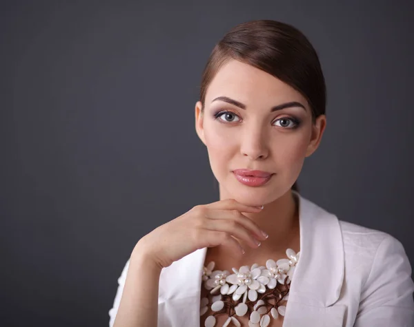 Portret van een jonge vrouw met parels, staande op een grijze achtergrond — Stockfoto