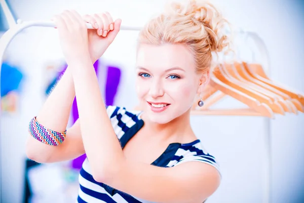 Mooie jonge stylist vrouw in de buurt van rack met hangers — Stockfoto