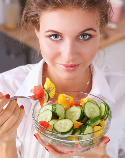 Ung kvinna äter färsk sallad i modernt kök — Stockfoto