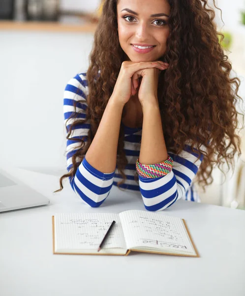 Smiling young woman with laptop in the kitchen at home — Stock Photo, Image