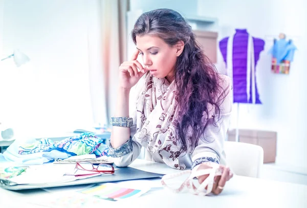 Glimlachende vrouwelijke mode-ontwerper zit aan het bureau — Stockfoto