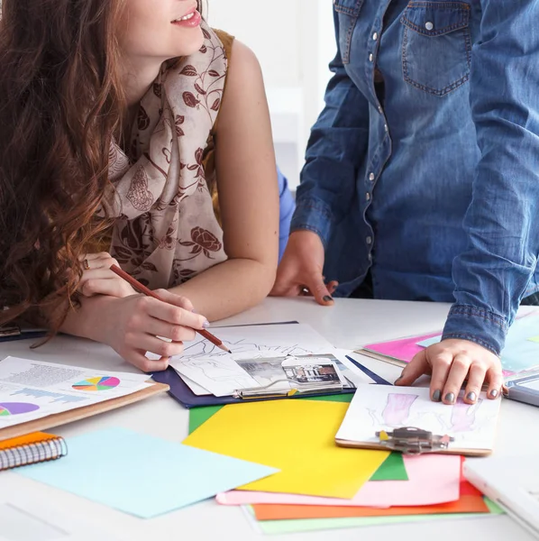 Young attractive female fashion designer working at office desk, drawing while talking on mobile — Stock Photo, Image