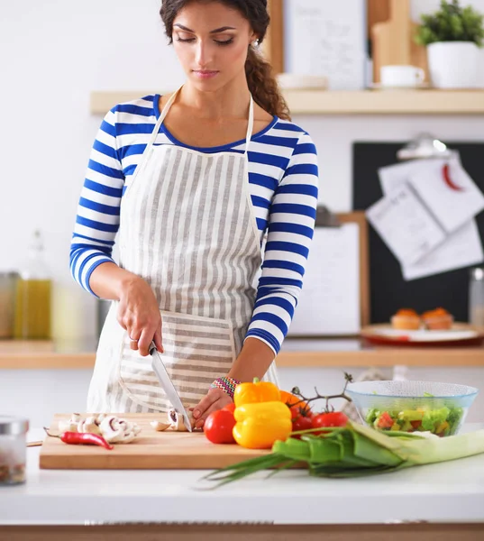 Jeune femme coupant des légumes dans la cuisine — Photo