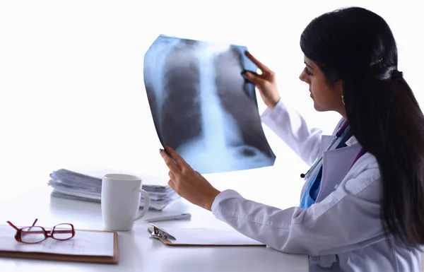 Young female doctor studying x-ray image, sitting at the desk Royalty Free Stock Photos