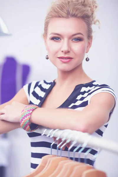 Vackra unga stylist kvinna nära rack med hängare — Stockfoto