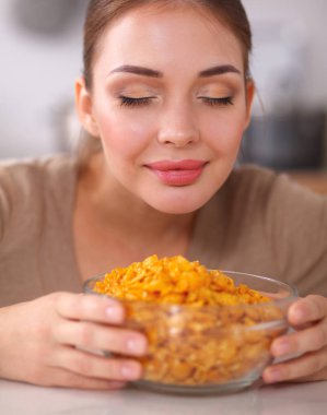 Gülümseyen çekici kadın mutfağın içinde kahvaltı yapıyor.