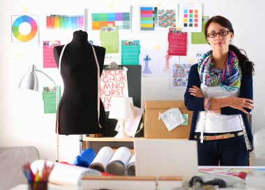 Güzel genç moda tasarımcısı stüdyoda duruyor.