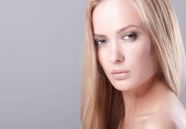 Gri arka planda izole edilmiş güzel bir kadının portresi.