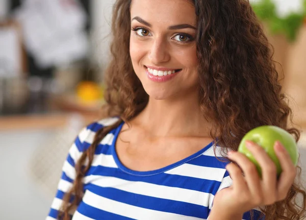 행복 한 젊은 여자가 부엌에서 사과를 먹다 — 스톡 사진