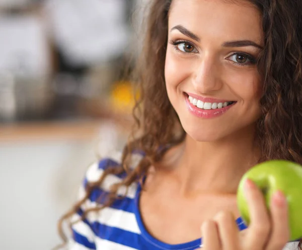 Šťastná mladá žena jíst jablka na kuchyni — Stock fotografie