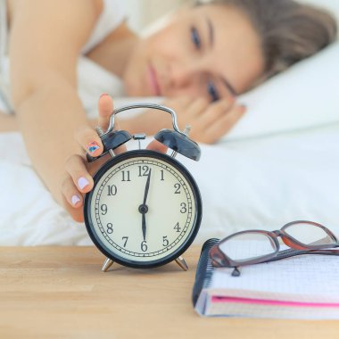 Genç bir kadın sabah alarmını erteliyor.