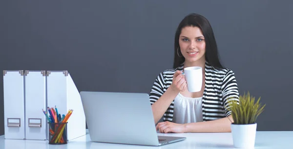 Jonge vrouw met een laptop zitten geïsoleerd op grijze achtergrond — Stockfoto