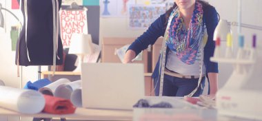 Güzel moda tasarımcısı stüdyoda duruyor.