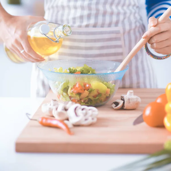 Jonge vrouw mengt verse salade — Stockfoto