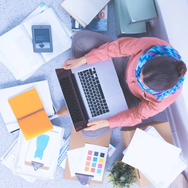 Junge attraktive Modedesignerin arbeitet am Schreibtisch und zeichnet, während sie mit dem Handy spricht — Stockfoto