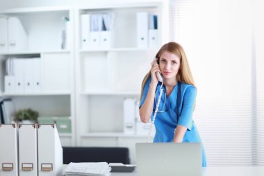 Kadın doktor teşhis merkezinde telefonla konuşuyor.